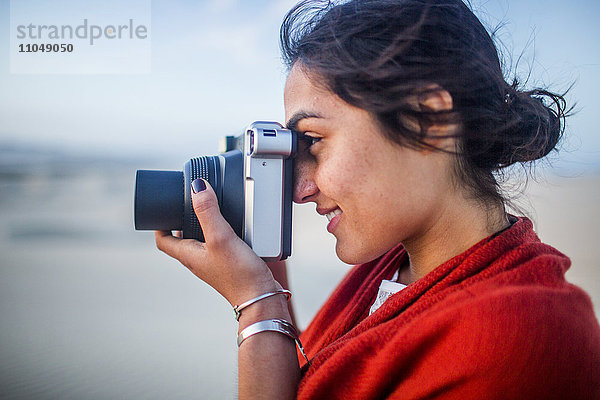 Gemischtrassige Frau beim Fotografieren in der Wüste