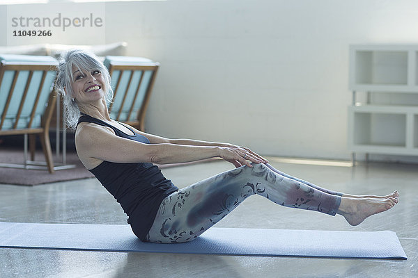 Frau macht Yoga und balanciert auf einer Übungsmatte