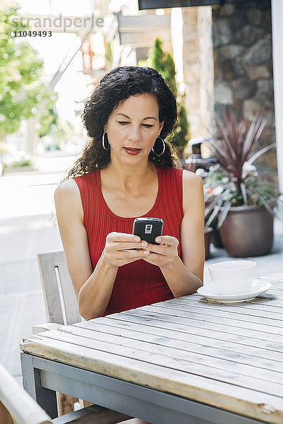 Mixed Race Frau texting auf Handy im Café