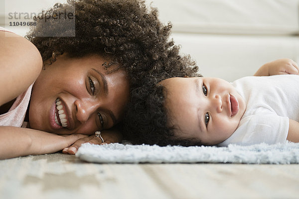 Mutter und kleiner Sohn liegen Kopf an Kopf auf dem Boden