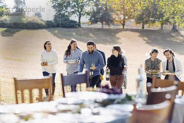 Freunde tragen das Essen zum Esstisch im Freien