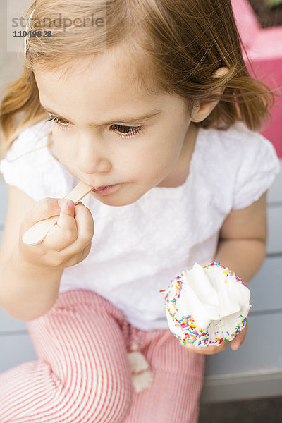 Kaukasisches Mädchen isst Eiscreme mit Löffel