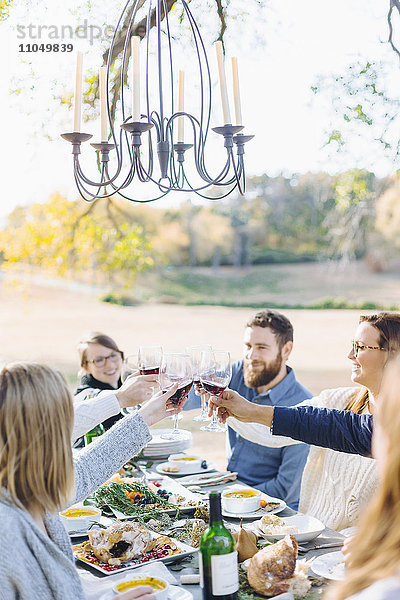 Freunde stoßen am Tisch im Freien mit Wein an