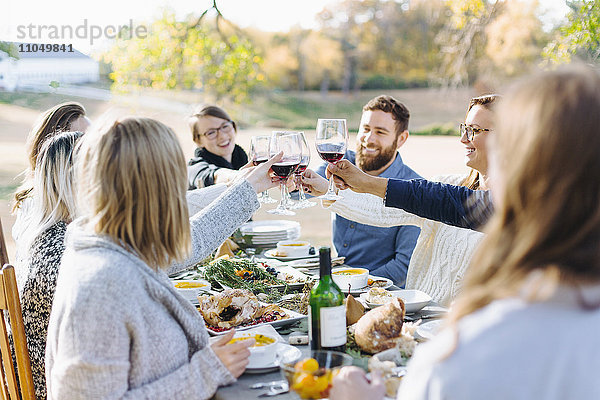 Freunde stoßen am Tisch im Freien mit Wein an