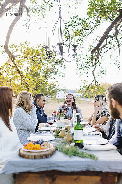 Freunde trinken Wein an einem Tisch im Freien