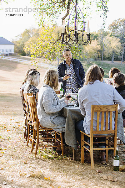 Freunde stoßen am Tisch im Freien mit Wein an