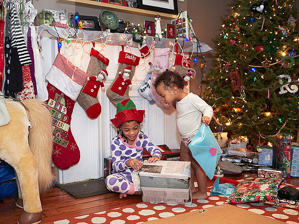 Gemischtrassige Kinder öffnen Weihnachtsgeschenke