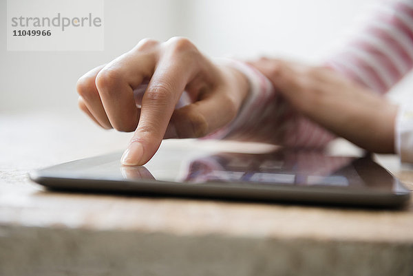 Hände einer hispanischen Frau  die ein digitales Tablet benutzt