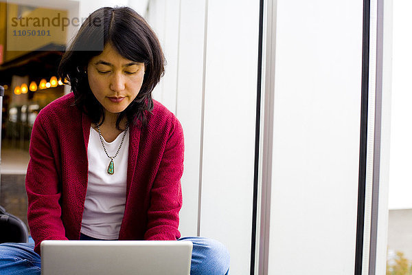 Japanerin im Schneidersitz mit Laptop