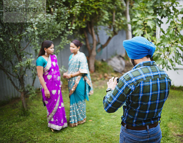 Mann fotografiert Frauen in traditionellen indischen Gewändern