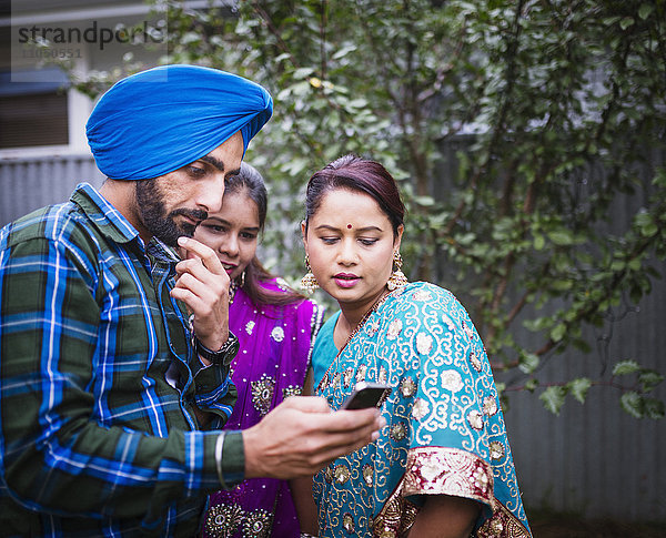 Familie in traditioneller indischer Kleidung mit Mobiltelefon