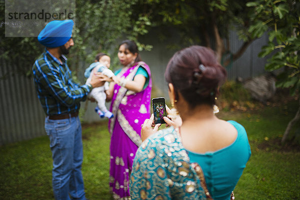Frau fotografiert Familie mit Mobiltelefon