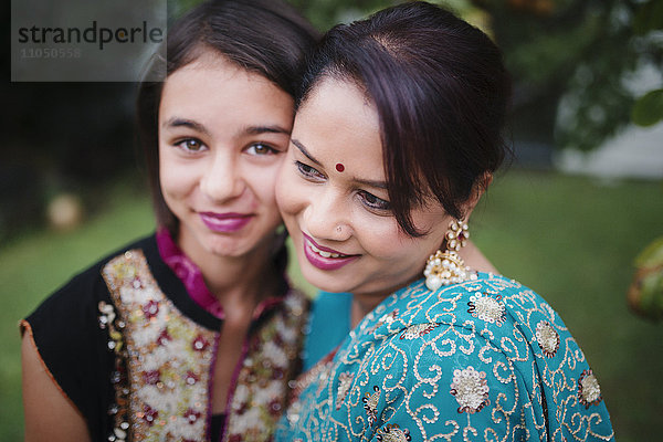 Mutter und Tochter in indischer Kleidung umarmen sich im Freien