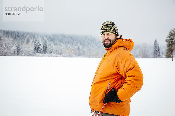 Kaukasischer Mann in verschneitem Feld stehend