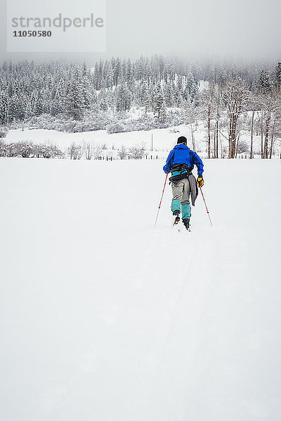 Kaukasische Frau beim Skilanglauf auf einem verschneiten Feld
