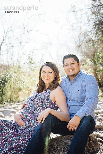 Schwangere Hispanic Paar lächelnd im Freien