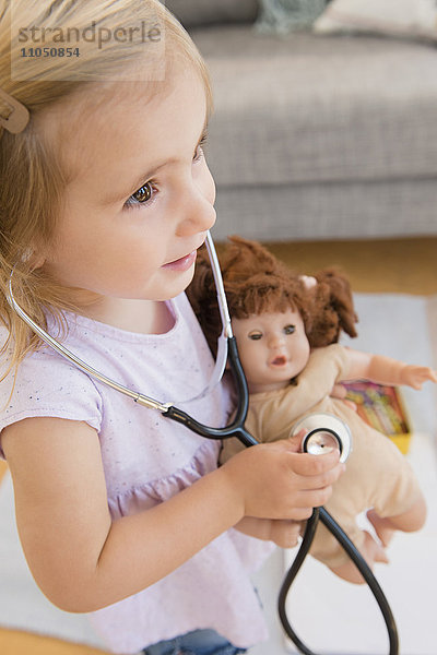 Kaukasisches Mädchen spielt Arzt mit Puppe