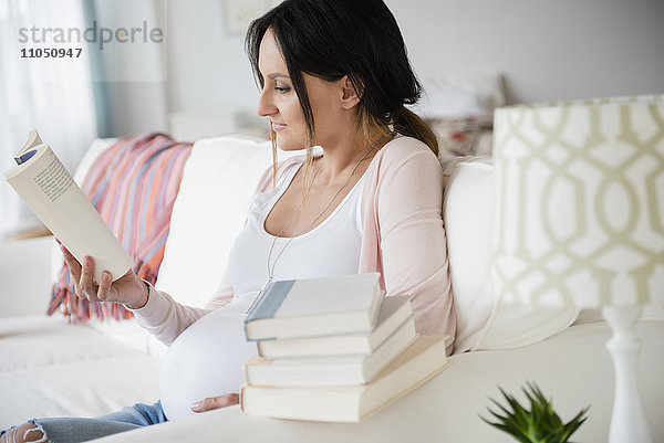 Schwangere kaukasische Frau liest Babybücher