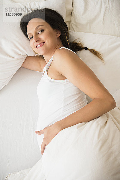 Schwangere kaukasische Frau auf dem Bett liegend