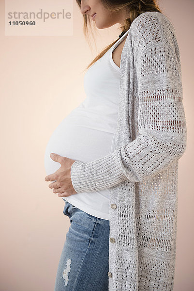 Schwangere kaukasische Frau hält ihren Bauch
