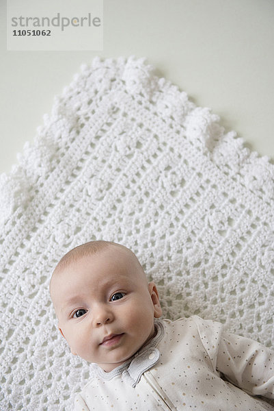Kaukasisches Baby liegt auf einer Decke
