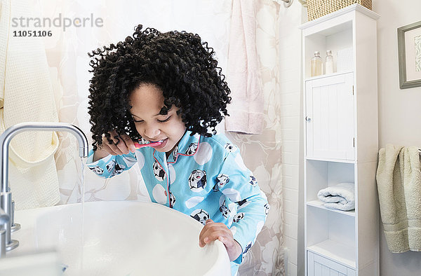 Afroamerikanisches Mädchen beim Zähneputzen im Badezimmer
