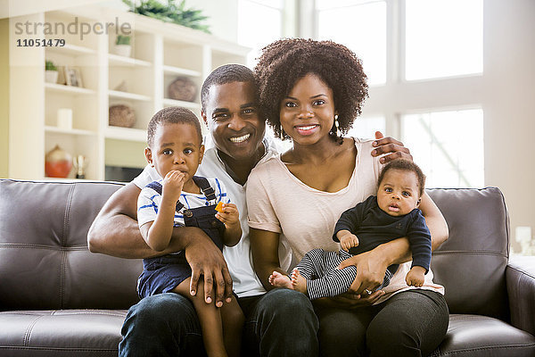 Lächelnde schwarze Familie posiert auf dem Sofa