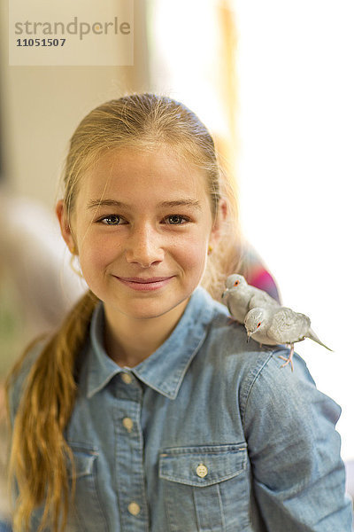 Kaukasisches Mädchen mit zwei Ziervögeln auf der Schulter stehend