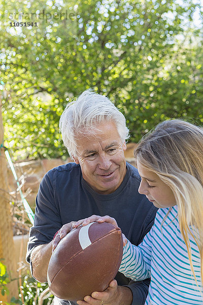 Kaukasischer Großvater zeigt seiner Enkelin  wie man einen Fußball hält