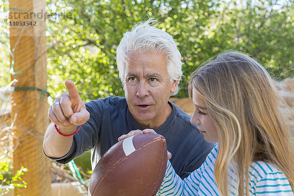 Kaukasischer Großvater zeigt seiner Enkelin  wie man einen Fußball zielt