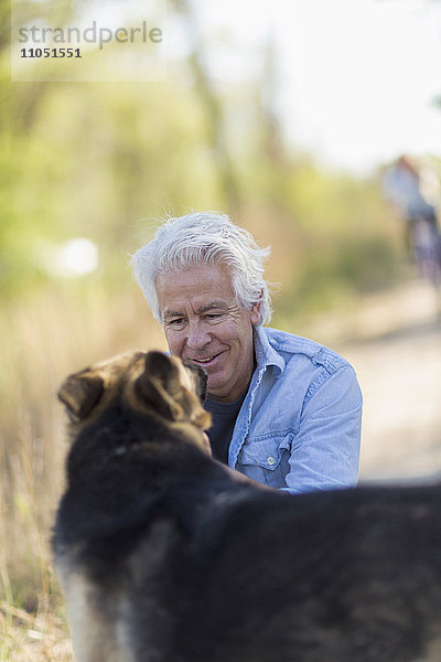 Kaukasischer Mann streichelt Hund Feldweg