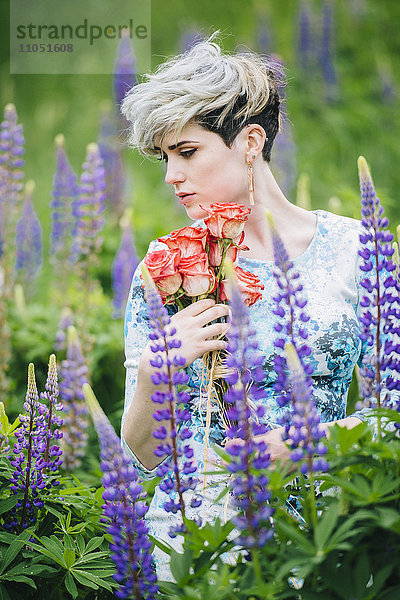 Kaukasische Frau hält Blumenstrauß in einem Blumenfeld