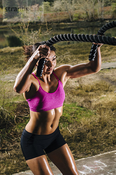 Gemischtrassige Frau trainiert mit schweren Seilen