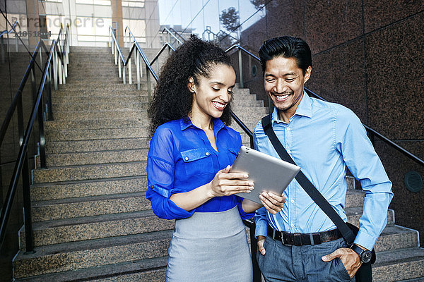 Lächelnde Geschäftsleute  die ein digitales Tablet im Freien benutzen