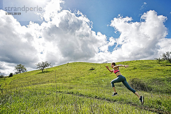 Kaukasische Frau läuft auf einem Hügel
