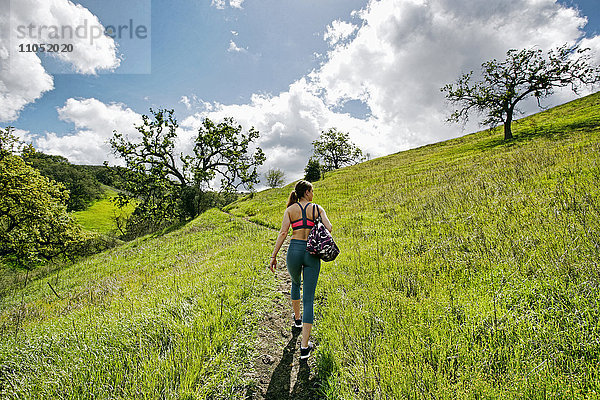 Kaukasische Frau geht auf einem Hügel und trägt eine Tasche