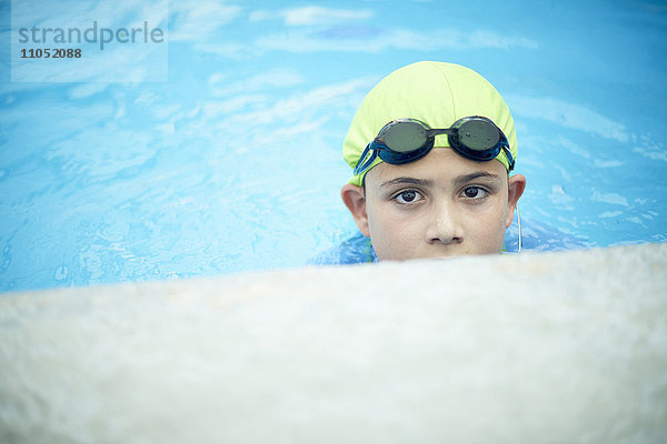 Hispanischer Junge schwimmt mit Badekappe und Schwimmbrille