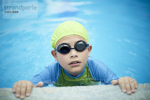 Hispanischer Junge schwimmt mit Badekappe und Schwimmbrille