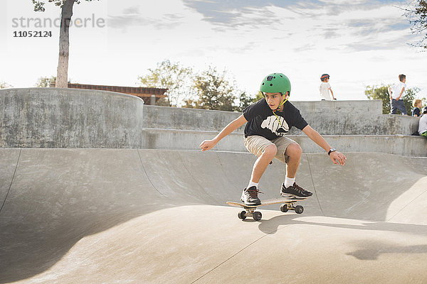 Gemischtrassiger Junge auf dem Skateboard im Skatepark