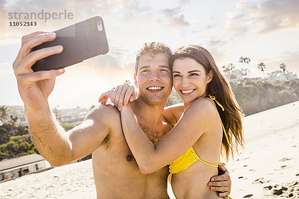 Kaukasisches Paar macht Selfie am Strand