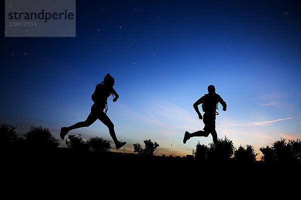 Silhouette eines kaukasischen Paares beim Laufen in der Morgendämmerung