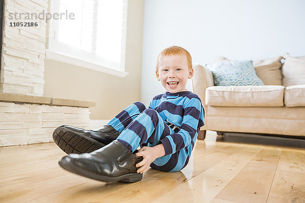 Kaukasischer Junge trägt Schuhe des Vaters im Wohnzimmer