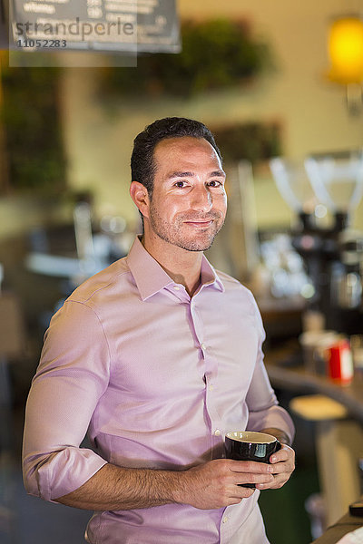 Hispanischer Geschäftsmann trinkt Kaffee in einem Coffeeshop