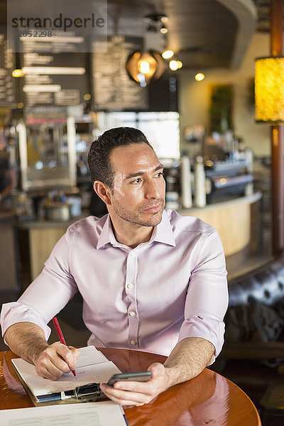 Hispanischer Geschäftsmann benutzt Mobiltelefon in einem Café