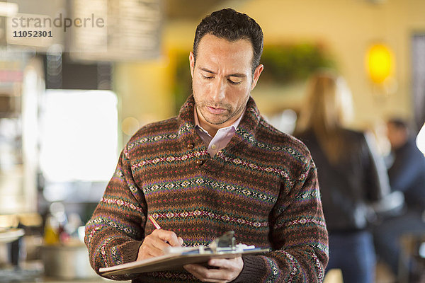 Hispanischer Geschäftsmann schreibt in einem Café
