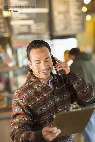 Hispanischer Geschäftsmann im Gespräch am Telefon in einem Café
