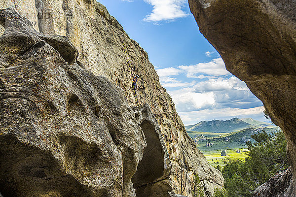 Entfernte kaukasische Frau klettert auf Felsen