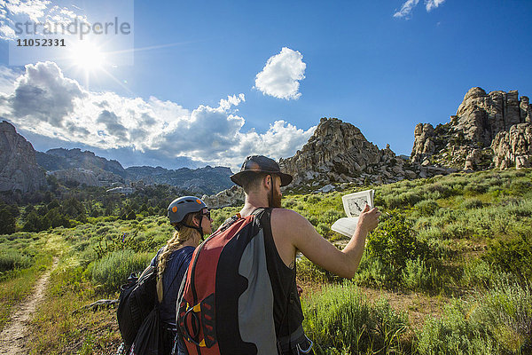 Kaukasisches Paar liest Reiseführer in der Nähe eines Berges