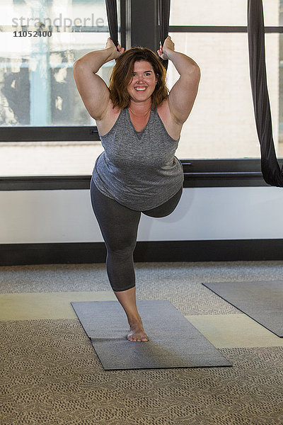 Frau beim Yoga an Seilen hängend