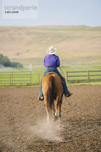 Cowboy beim Reiten auf einer Ranch